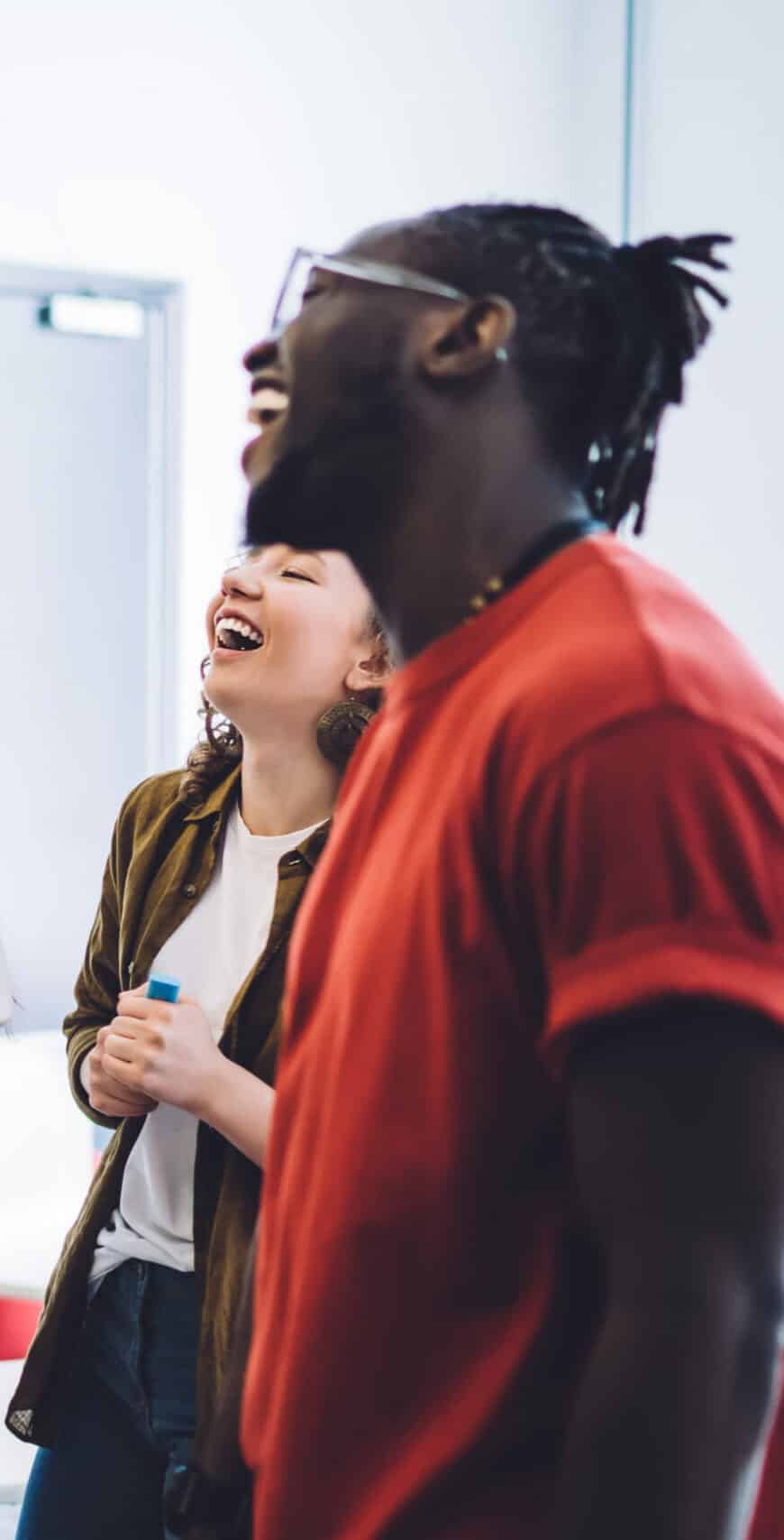 Une jeune femme et un jeune homme souriants au tableau de la classe en train de suivre une formation disc