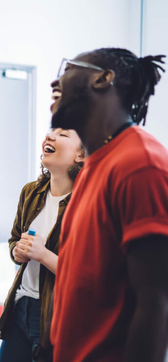 Une jeune femme et un jeune homme souriants au tableau de la classe en train de suivre une formation disc