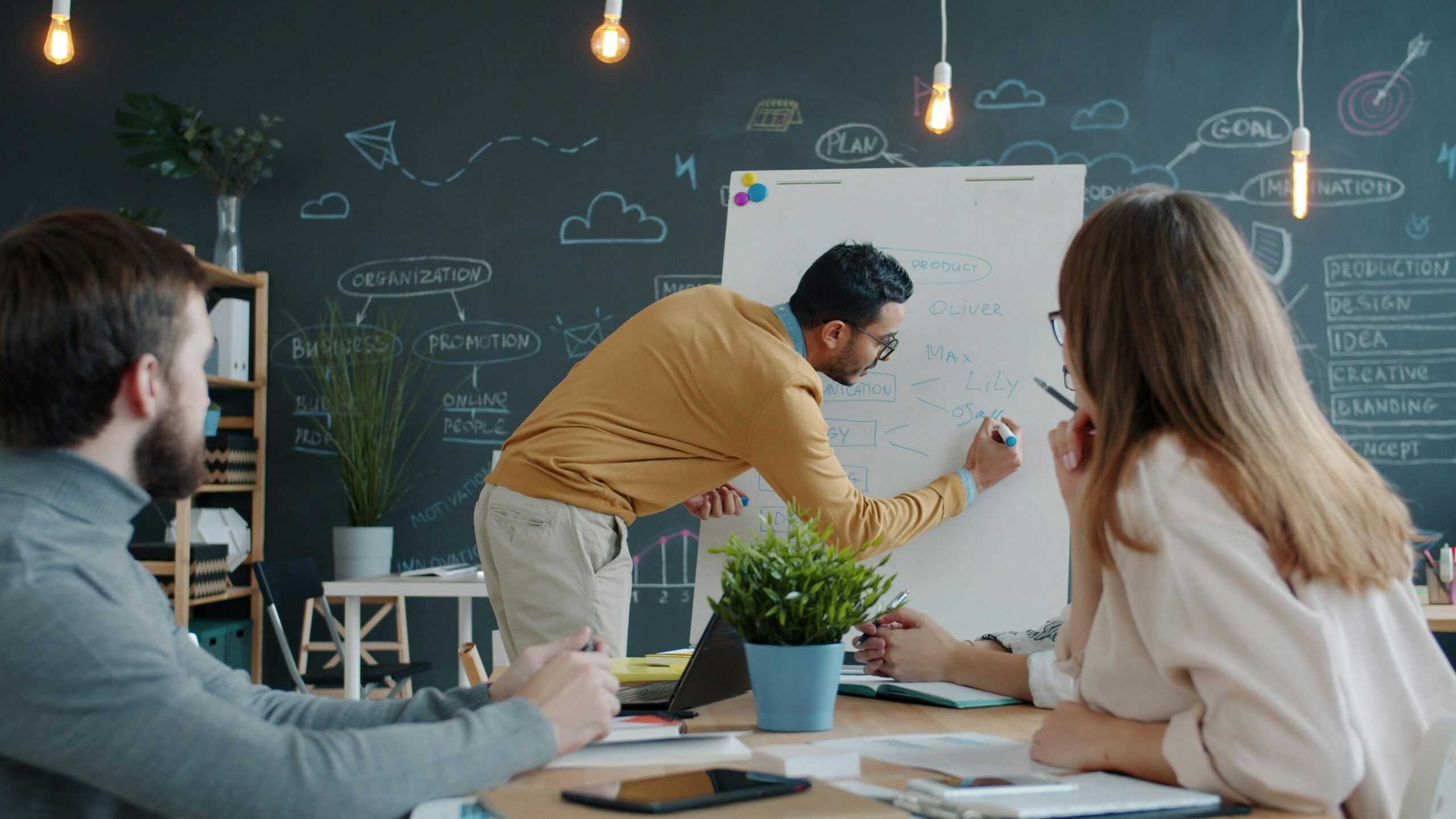 Un jeune qui écrit sur un tableau blanc en réunion de brainstorming